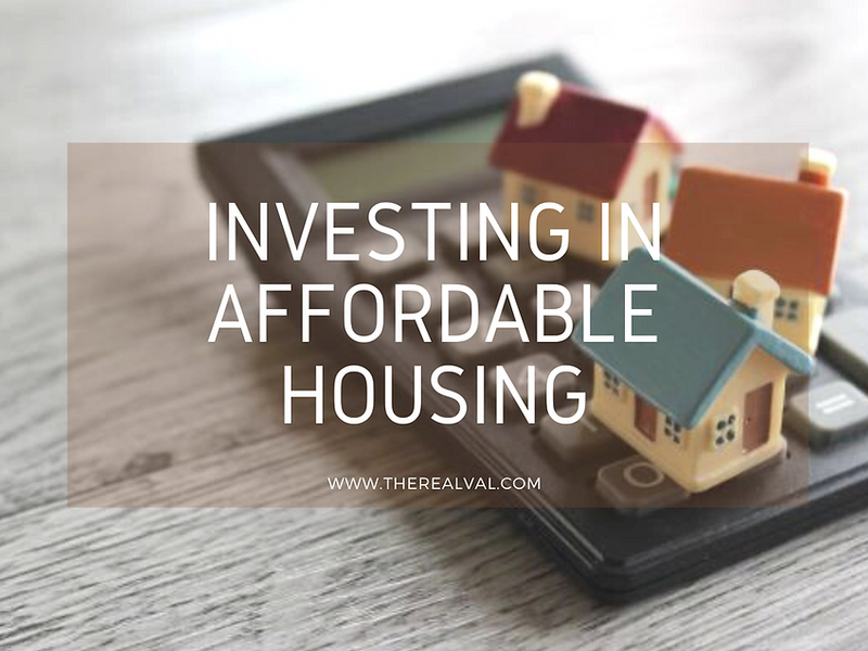 Alt text: Investing in affordable housing text over miniature houses on a calculator, highlighting property investment