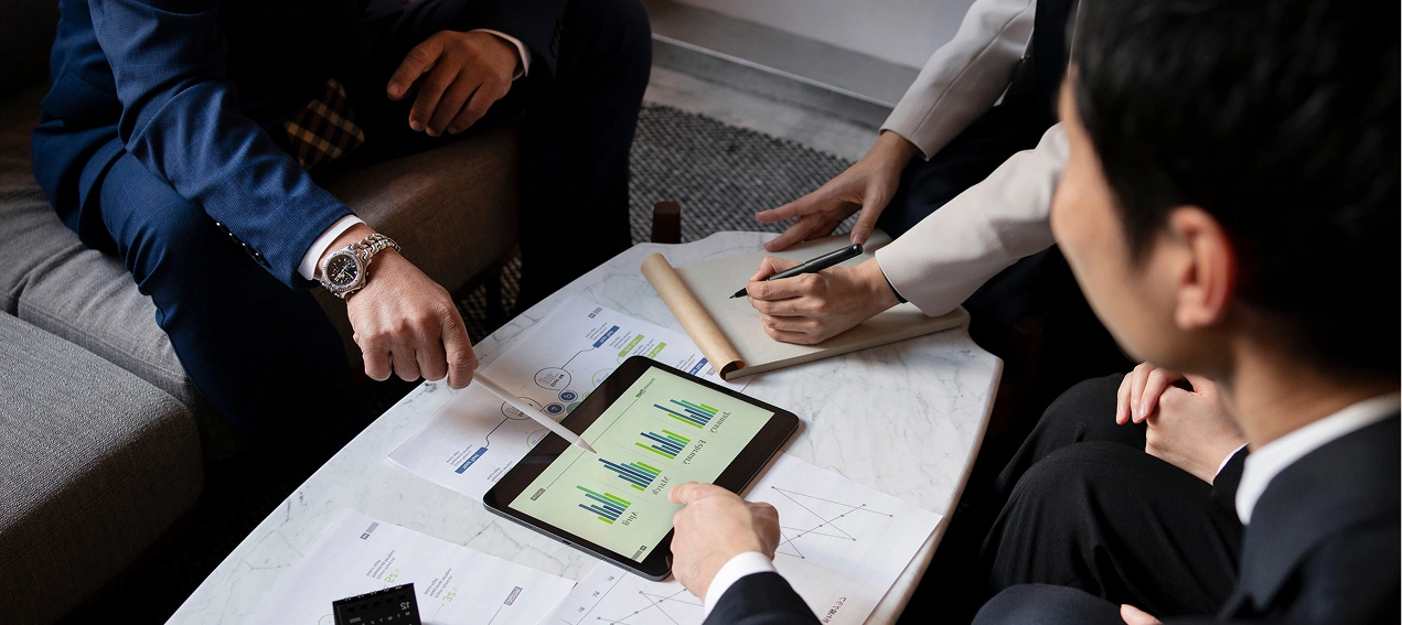 Business team analyzing financial charts on a tablet during a meeting.